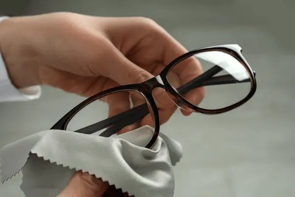 Hands cleaning a pair of eyeglasses with a soft cloth